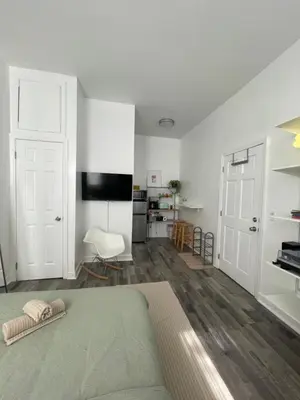 a white room with a bed and a kitchen at Cozy Private studio in Bushwick in Brooklyn