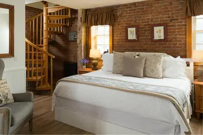 a bedroom with a large bed and a brick wall at Four Chimneys Inn in Bennington