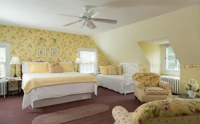 a bedroom with two beds and a couch and a fan at Four Chimneys Inn in Bennington
