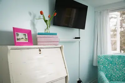 a room with a dresser and a vase with flowers on it at Four Chimneys Inn in Bennington