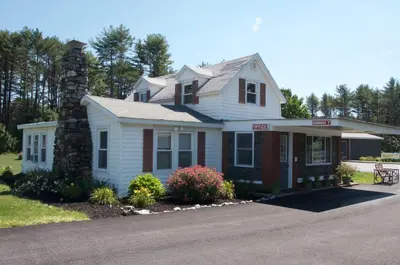 a white house with a chimney on a street at Sara Glen Motel - Saratoga Springs-Glens Falls in Saratoga Springs