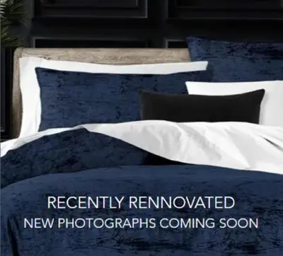 a bed with blue and white sheets and pillows at The Stockade Inn in Schenectady