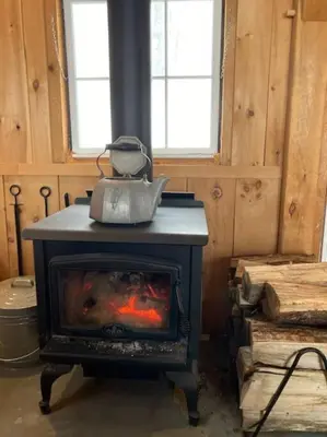 a woodburning stove with a kettle on top of it at Sadawga Springs Retreat in Whitingham