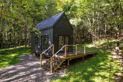 a small black cabin with a porch and a deck at Lil' Rita in Bloomville