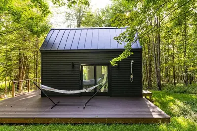 a black tiny house with a hammock on a deck at Lil' Rita in Bloomville