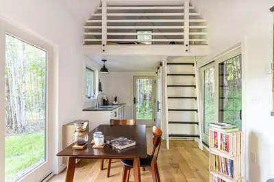 a dining room with a table and a spiral staircase at Lil' Rita in Bloomville