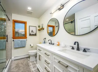 a bathroom with a sink and a toilet and a mirror at Mountain Blue Vista - Luxury retreat near Ski resorts with Pond, Firepit and Hot Tub in Windham