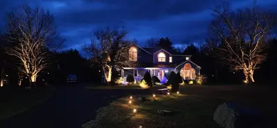 a house with christmas lights in the yard at night at Mountain Blue Vista - Luxury retreat near Ski resorts with Pond, Firepit and Hot Tub in Windham