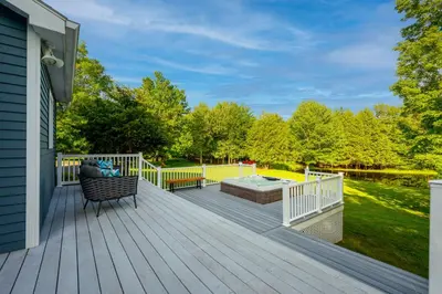 a deck with a hot tub and a bench at Mountain Blue Vista - Luxury retreat near Ski resorts with Pond, Firepit and Hot Tub in Windham