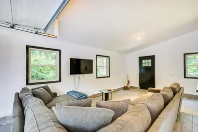 a living room with a large couch and a tv at Lakefront New York Abode with Deck, Grill and Fire Pit in Mahopac