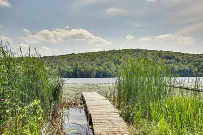 a wooden bridge over a body of water at Lakefront New York Abode with Deck, Grill and Fire Pit in Mahopac