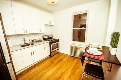 a kitchen with white cabinets and a wooden floor at Urban Bedroom in Mount Vernon