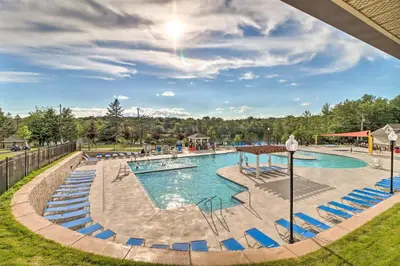a pool at a resort with blue chairs at On-Site Lakes and Pools Inviting Tobyhanna Home! in Tobyhanna