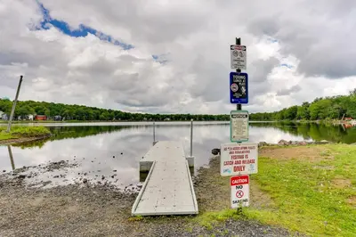 a pier in front of a body of water with signs at On-Site Lakes and Pools Inviting Tobyhanna Home! in Tobyhanna