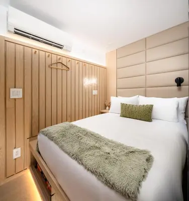 a bedroom with a large white bed with a green rug on it at Little Charlie Hotel in New York