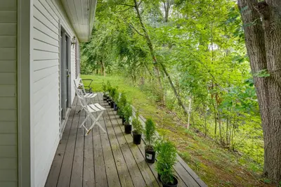 a porch with a bench and potted plants on it at Lakefront West Sand Lake Home with Beach Access! in West Sand Lake
