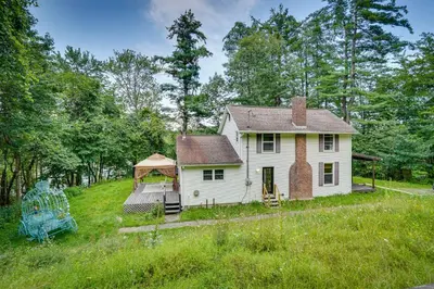 a white house on a hill in a field at Lakefront West Sand Lake Home with Beach Access! in West Sand Lake