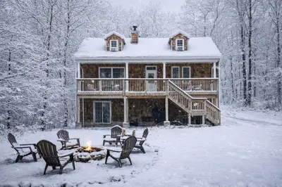 a log cabin in the snow with a fire at Catskill Cabin with Firepit & Indoor Jacuzzi Tub in Catskill