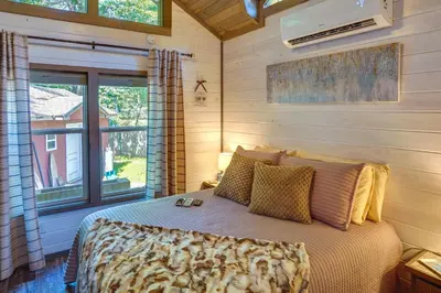 a bedroom with a bed and a large window at Mayfield Tiny Home with Porch, Walk to Beaches! in Benson
