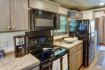 a kitchen with a stove and a refrigerator at Mayfield Tiny Home with Porch, Walk to Beaches! in Benson