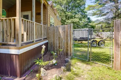 a fence in front of a house with a yard at Mayfield Tiny Home with Porch, Walk to Beaches! in Benson