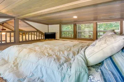 a large bed in a room with windows and a tv at Mayfield Tiny Home with Porch, Walk to Beaches! in Benson