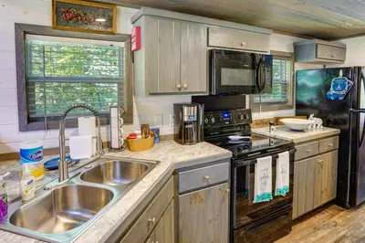a kitchen with a sink and a stove at Mayfield Tiny Home with Porch, Walk to Beaches! in Benson