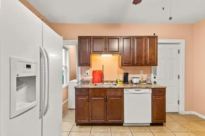 a kitchen with wooden cabinets and a white refrigerator at Cozy Retreat, Steps to Yale Bridgeport Hospital in Bridgeport