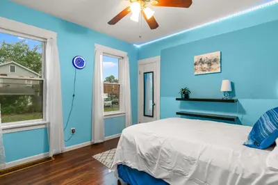 a blue bedroom with a bed and two windows at Cozy Retreat, Steps to Yale Bridgeport Hospital in Bridgeport