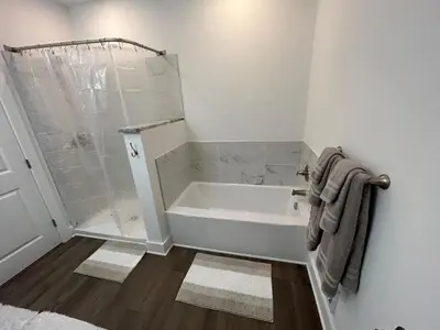 a white bathroom with a tub and a shower at NEW 3 bedroom - Thoroughbred Farm & Lake Views! in Saratoga Springs