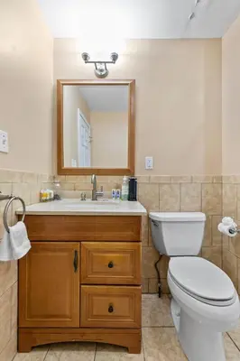 a bathroom with a toilet and a sink with a mirror at Bridgeport Bliss Solo Haven Near Yale & Downtown in Bridgeport
