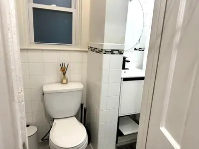 a white bathroom with a toilet and a mirror at 3-A Diamond in Yonkers, NY in Yonkers