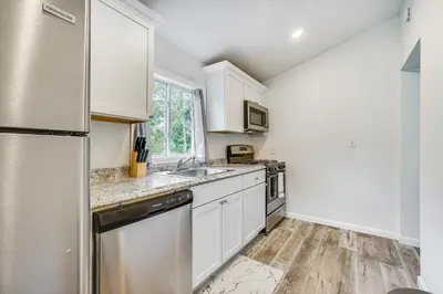 a kitchen with white cabinets and a stainless steel refrigerator at Cozy Glens Falls Getaway Less Than 1 Mi to Downtown in Glens Falls