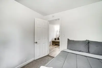 a white bedroom with a bed and a door at Cozy Glens Falls Getaway Less Than 1 Mi to Downtown in Glens Falls