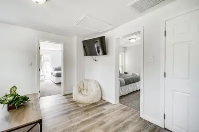 a white room with a chair and a bedroom at Cozy Glens Falls Getaway Less Than 1 Mi to Downtown in Glens Falls