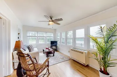 a living room with a ceiling fan and windows at Hudson River Vista in Queensbury