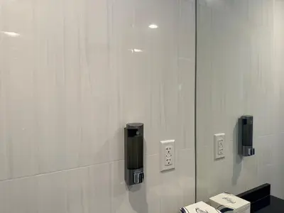a bathroom with a wall with a mirror and a sink at Regal Inn & Suites New York LaGuardia Hotel in Flushing