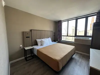 a hotel room with a bed and a large window at Regal Inn & Suites New York LaGuardia Hotel in Flushing