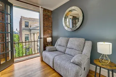 a living room with a couch and a mirror at Contemporary Cohoes Retreat with Electric Fireplace! in Cohoes