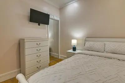 a bedroom with a bed and a dresser with a television at Contemporary Cohoes Retreat with Electric Fireplace! in Cohoes