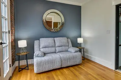 a living room with a chair and a mirror at Contemporary Cohoes Retreat with Electric Fireplace! in Cohoes