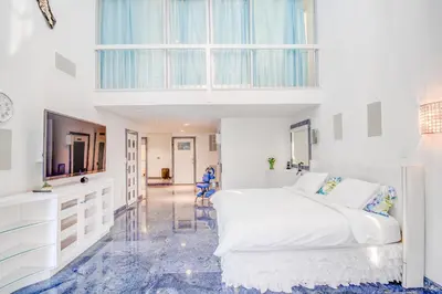 a white bedroom with a large bed and a tv at GABLES new 2024 in Bayside