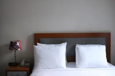 a bedroom with a bed with white pillows and a phone at Midtown West Hotel in New York