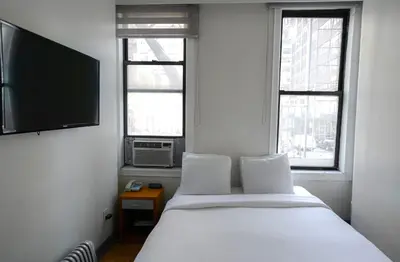 a bedroom with a bed and a flat screen tv at Midtown West Hotel in New York