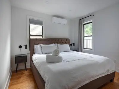 a white bedroom with a large bed with a stuffed animal on it at Three Bedroom Brooklynite Suite! in Brooklyn