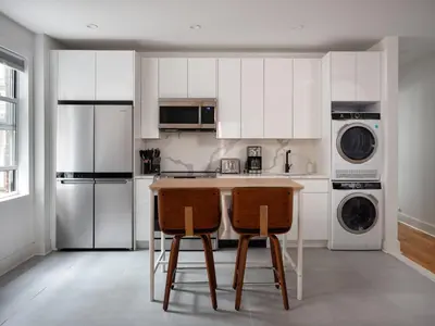 a kitchen with white cabinets and two bar stools at Three Bedroom Brooklynite Suite! in Brooklyn