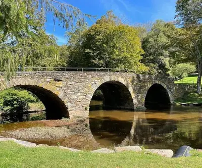 a stone bridge over a river in a park at Bethel Woods Cabin in Mongaup Valley