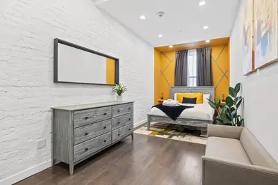 a bedroom with a bed and a white brick wall at SWJ 2nd - Times SQ, Brooklyn Bridge, LGA in 15 min in New York