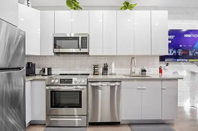 a kitchen with white cabinets and stainless steel appliances at SWJ 2nd - Times SQ, Brooklyn Bridge, LGA in 15 min in New York