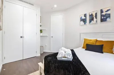 a white bedroom with a large white bed with yellow pillows at SWJ 5th - Perfect for Tourism: Near Train, Times Sq, Dining in New York